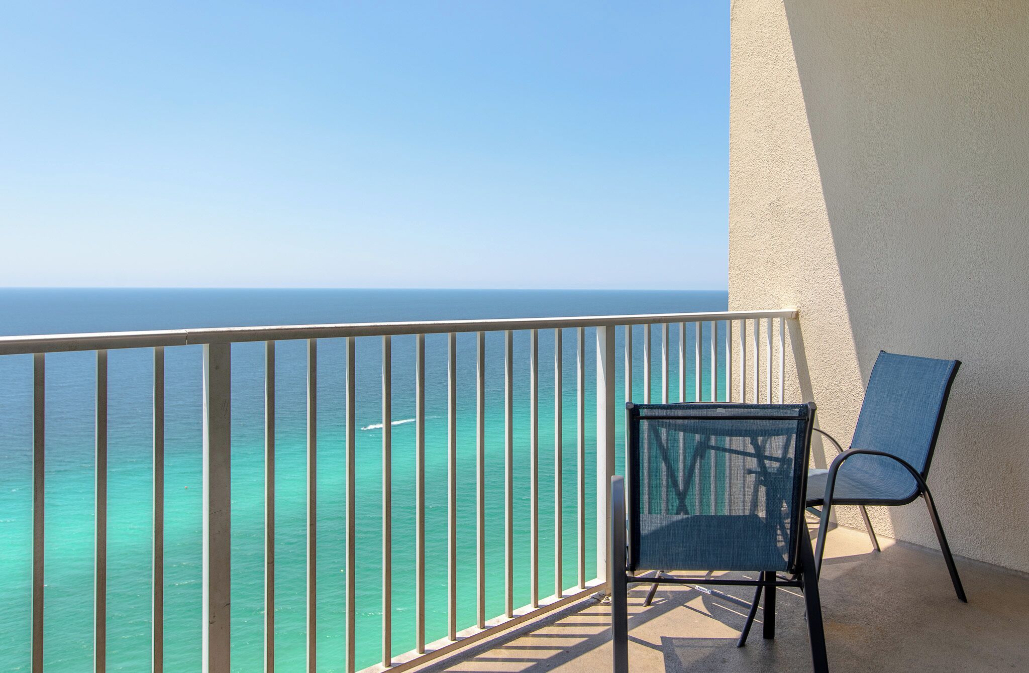 Ein Balkon mit Blick auf das Meer, ein Stuhl und eine Wand.