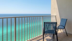 Ein Balkon mit Blick auf das Meer, ein Stuhl und eine Wand.