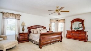 A bedroom with a wooden bed, a ceiling fan, a dresser, and a chair. - Extravagant Resort styles  5 bedrooms / 5 baths/ pool and hot tub (Davenport)