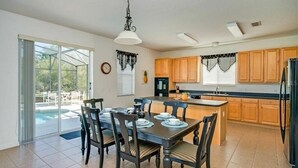 A spacious kitchen with wooden cabinets, a central island, and a dining area with a table set for four. - Extravagant Resort styles  5 bedrooms / 5 baths/ pool and hot tub (Davenport)