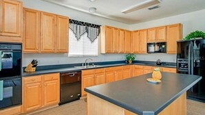 A modern kitchen with wooden cabinets, a central island, and stainless steel appliances. - Extravagant Resort styles  5 bedrooms / 5 baths/ pool and hot tub (Davenport)