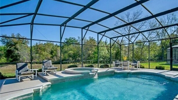 A covered outdoor swimming pool with lounge chairs and a hot tub. - Extravagant Resort styles  5 bedrooms / 5 baths/ pool and hot tub (Davenport)