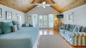 A bedroom with a large bed, a sofa, a ceiling fan, and a TV. - Located Across From Beach in Seaside, Wrap-Around Porches + 2 Adult Bikes! (Santa Rosa Beach)