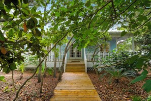A wooden pathway leading to a house with a porch. - Located Across From Beach in Seaside, Wrap-Around Porches + 2 Adult Bikes! (Santa Rosa Beach)