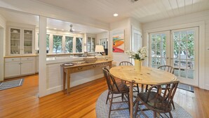 A spacious kitchen with wooden cabinets, a dining table, and chairs. - Located Across From Beach in Seaside, Wrap-Around Porches + 2 Adult Bikes! (Santa Rosa Beach)