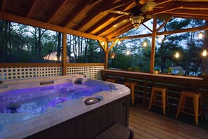 A wooden deck with a hot tub, wooden bar stools, and a view of trees. - Gunks Cottage Fire Pit, Hot Tub, Near Minnewaska Park (Kerhonkson)