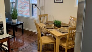 A dining area with a wooden table set for four, a ceiling fan, and a window with a view of a brick building. - The Gorge View Villa-with Yard & Parking (Niagara Falls)