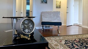 A living room with a vintage clock, a fur-covered chair, and a patterned rug. - The Gorge View Villa-with Yard & Parking (Niagara Falls)