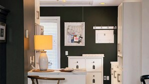 A modern kitchen with a central island, white cabinetry, and a dark accent wall. - Private Elora Studio in heart of Elora (Elora)