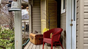 A porch with a wooden bench, a suitcase, and a red chair. - Private Elora Studio in heart of Elora (Elora)