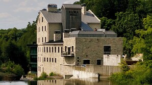 A large stone building with a sign reading "ELORA MILL" reflecting in a calm body of water. - Private Elora Studio in heart of Elora (Elora)