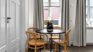 A dining area with a round table and four wicker chairs, a vase with flowers, and a window with curtains. - Superior Apartment Su (Reykjavík)