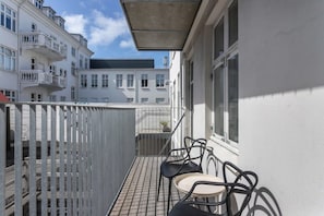 A balcony with a metal railing, two chairs, and a small table.