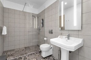 Um banheiro moderno com chuveiro, vaso sanitário e pia.
