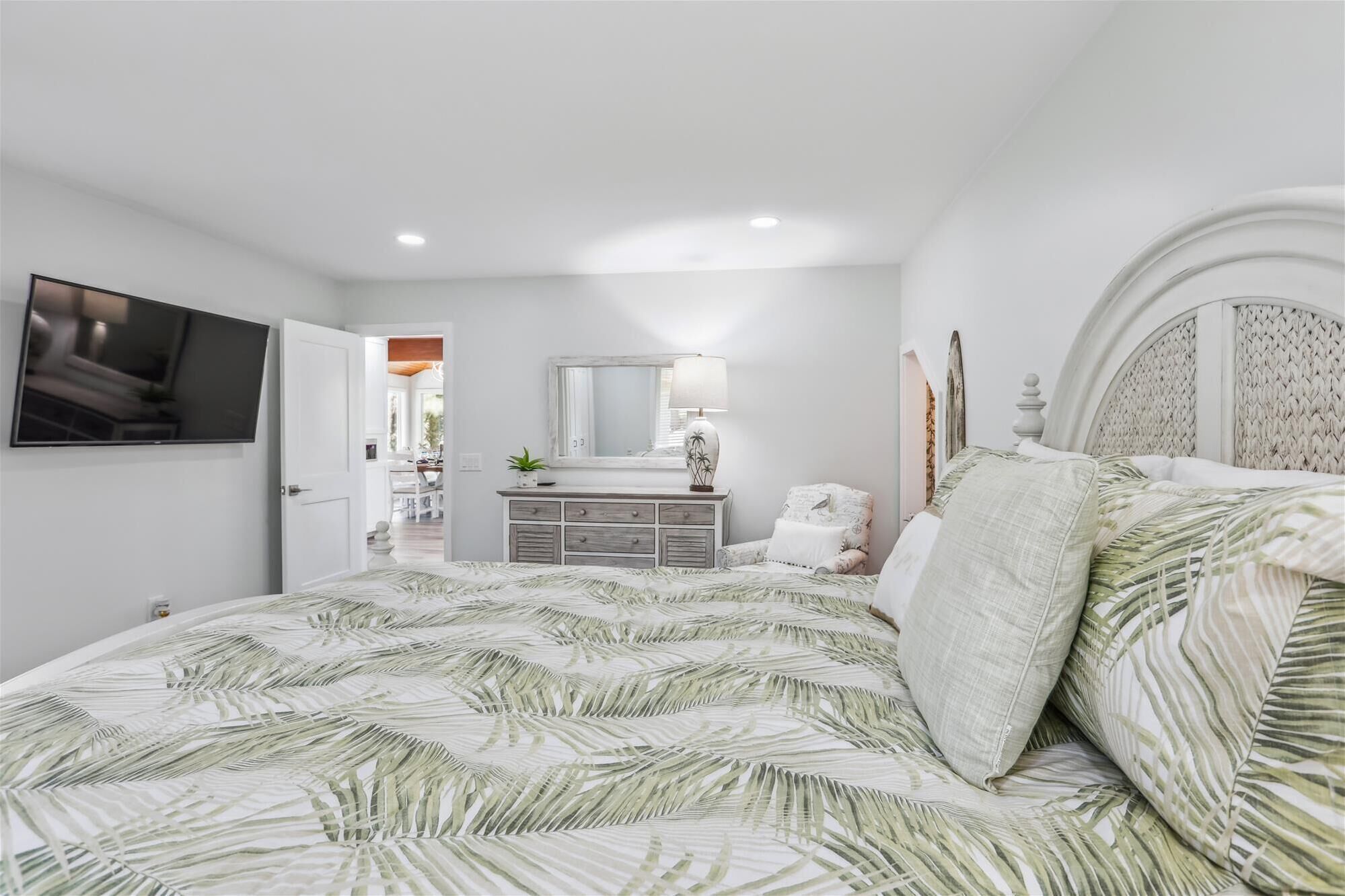 Un dormitorio con cama, cómoda, espejo y televisor.