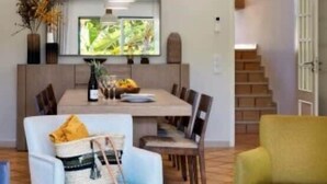 Un salon moderne comprenant un coin repas, un canapé, une table basse et un téléviseur fixé au mur.