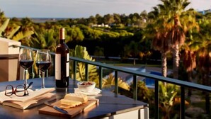 Un balcon avec une table dressée pour un repas, une bouteille de vin et des verres.