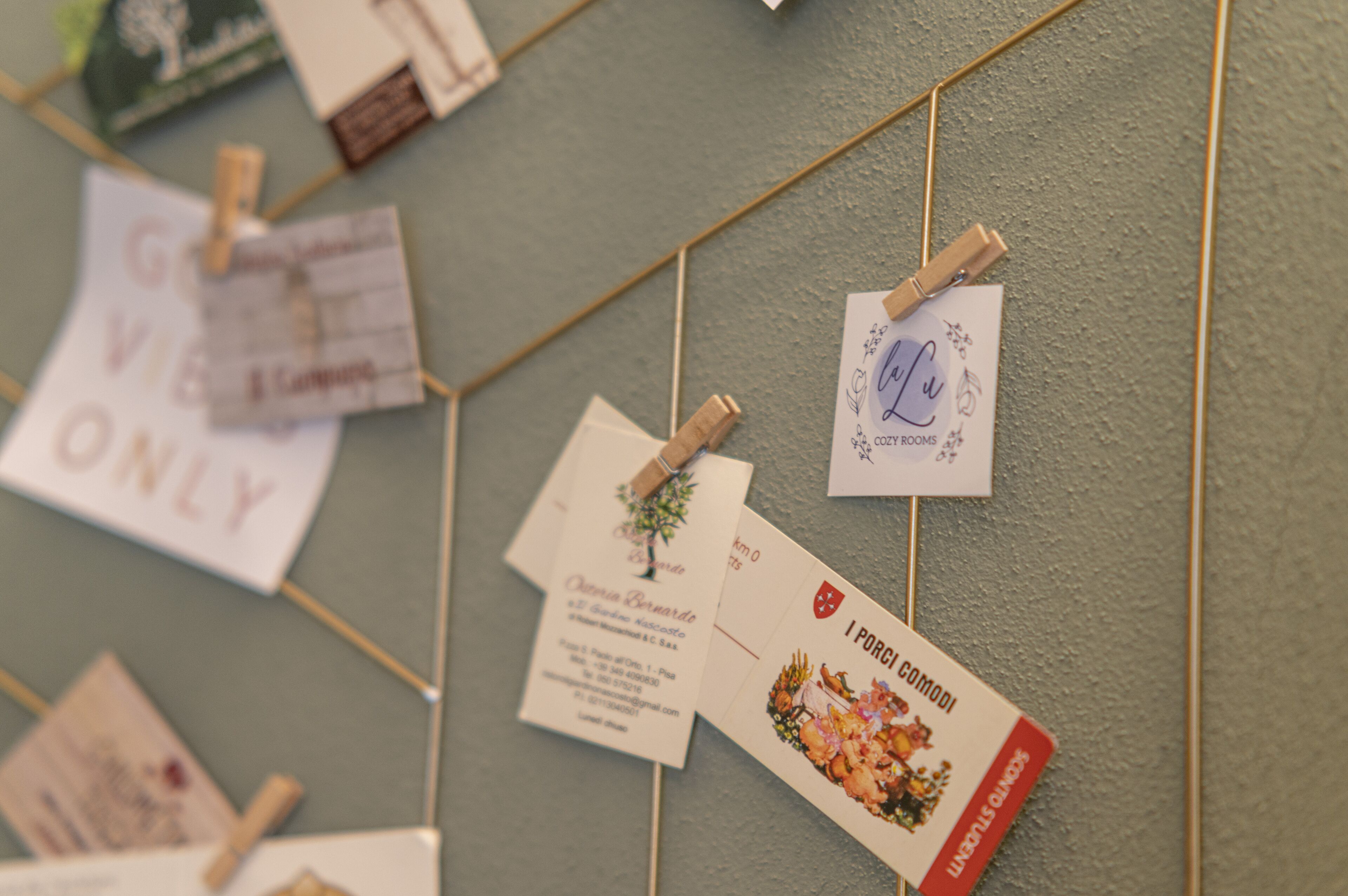 Un mur sur lequel sont accrochées diverses cartes de visite et des notes, maintenues par des pinces à linge.