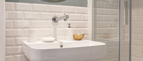 A bathroom with a white sink, a mirror, and a glass shower enclosure.