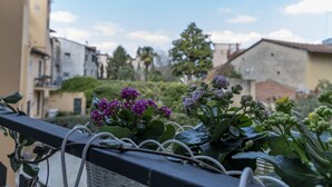 A balcony with potted plants and flowers, overlooking a residential area with buildings and trees. - La Lu Cozy Rooms 2 (Pisa)