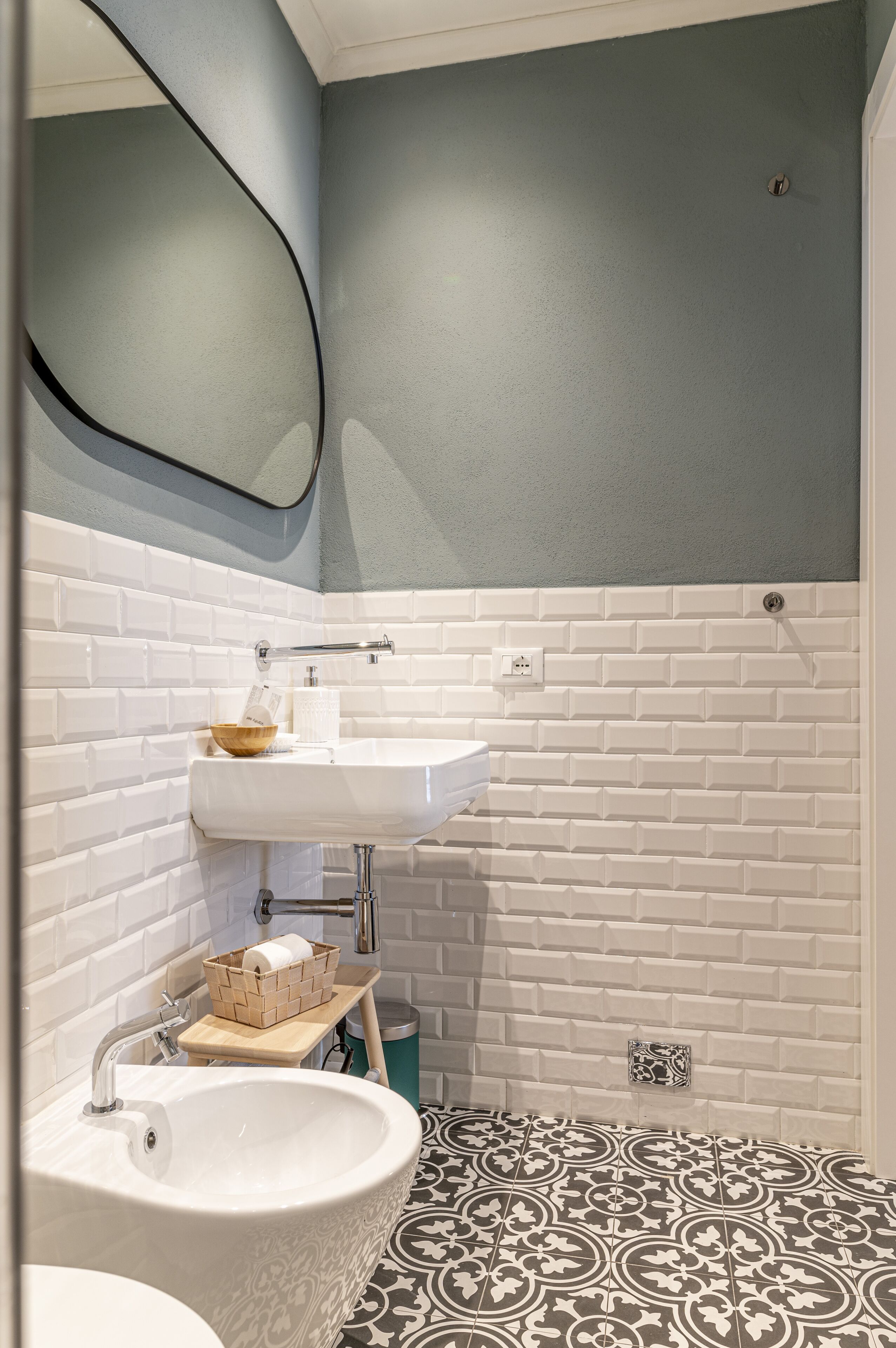 A bathroom with a white sink, a mirror, and a patterned floor.