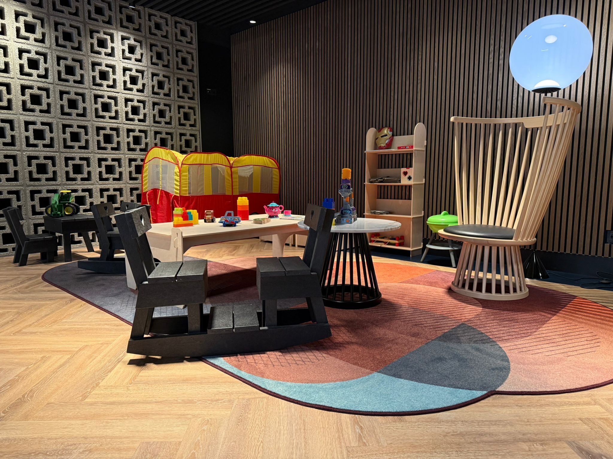 A modern playroom with a wooden floor, a play tent, and a variety of toys.