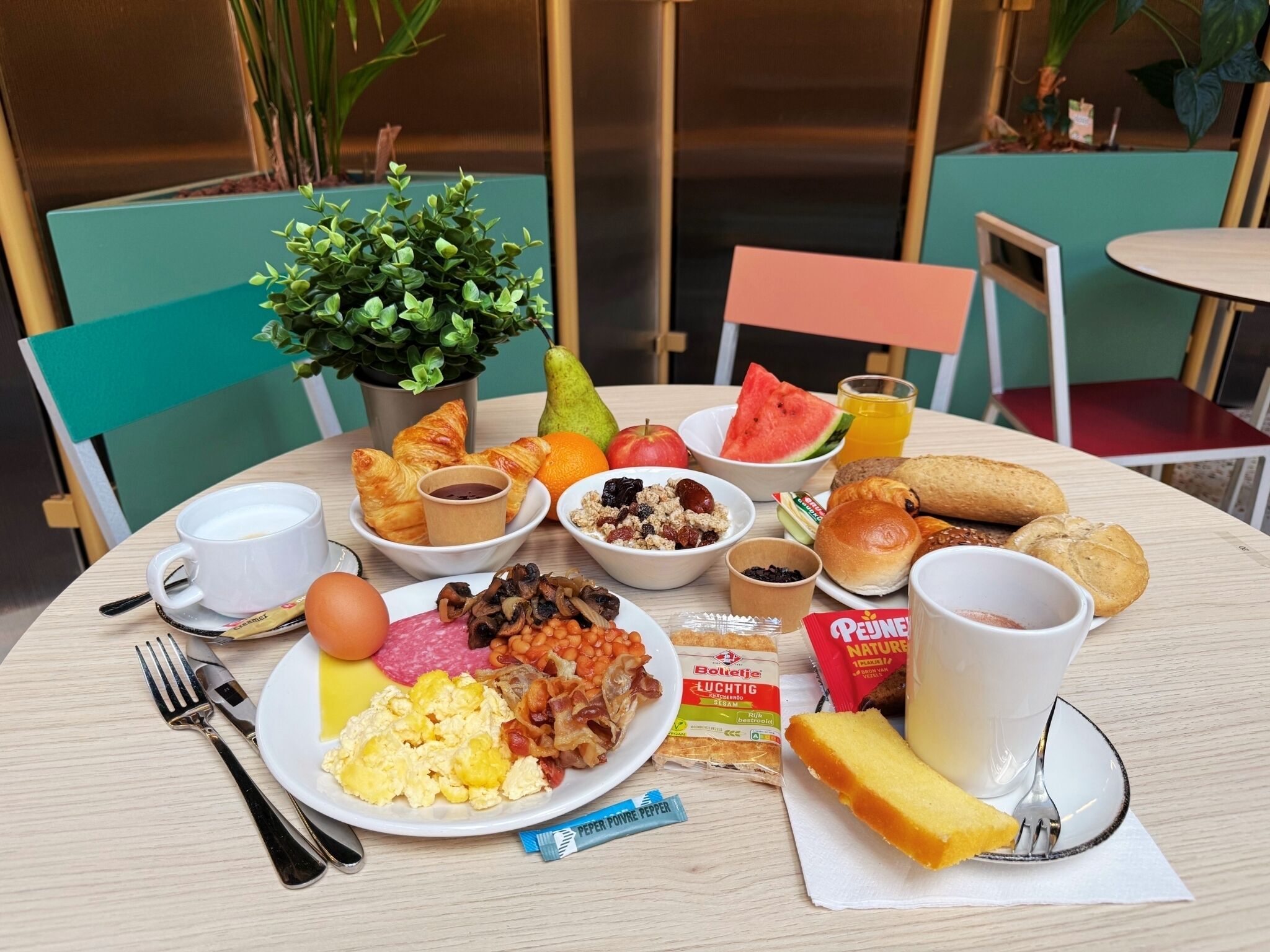 Ein Frühstückstisch mit verschiedenen Speisen, einer Kaffeetasse und einer kleinen Pflanze.