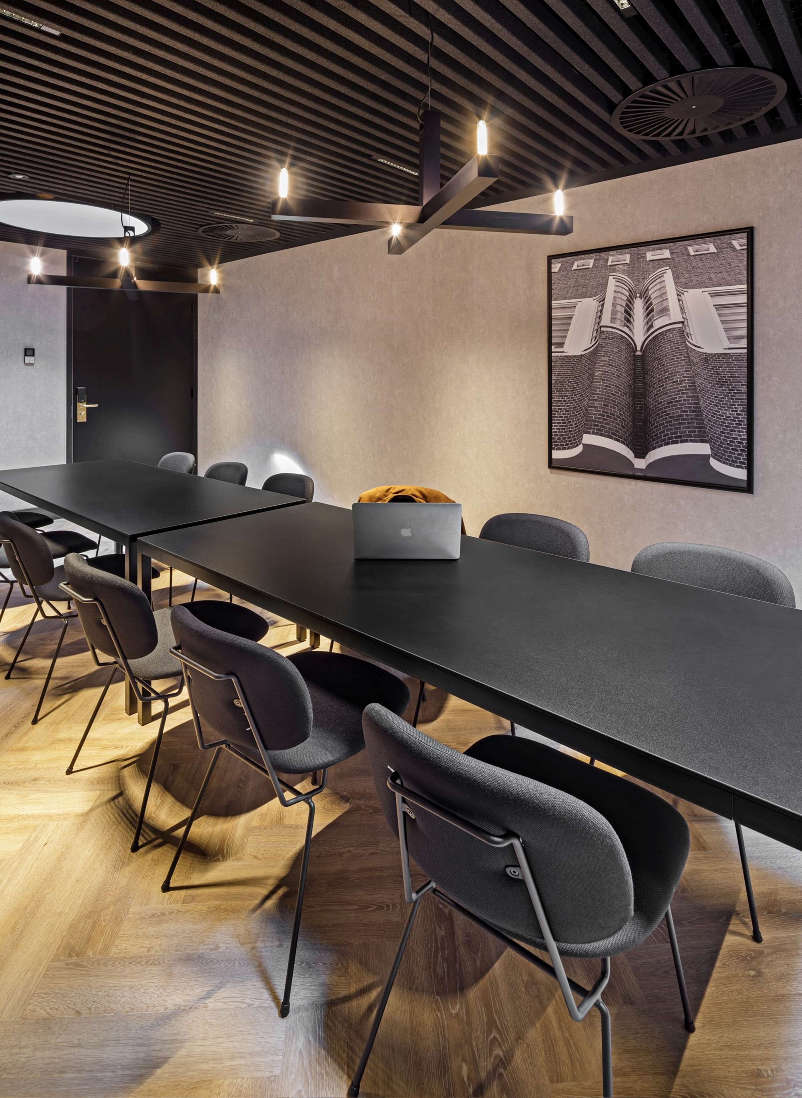 Une salle de conférence avec une longue table, des chaises modernes et un ordinateur portable posé sur la table.
