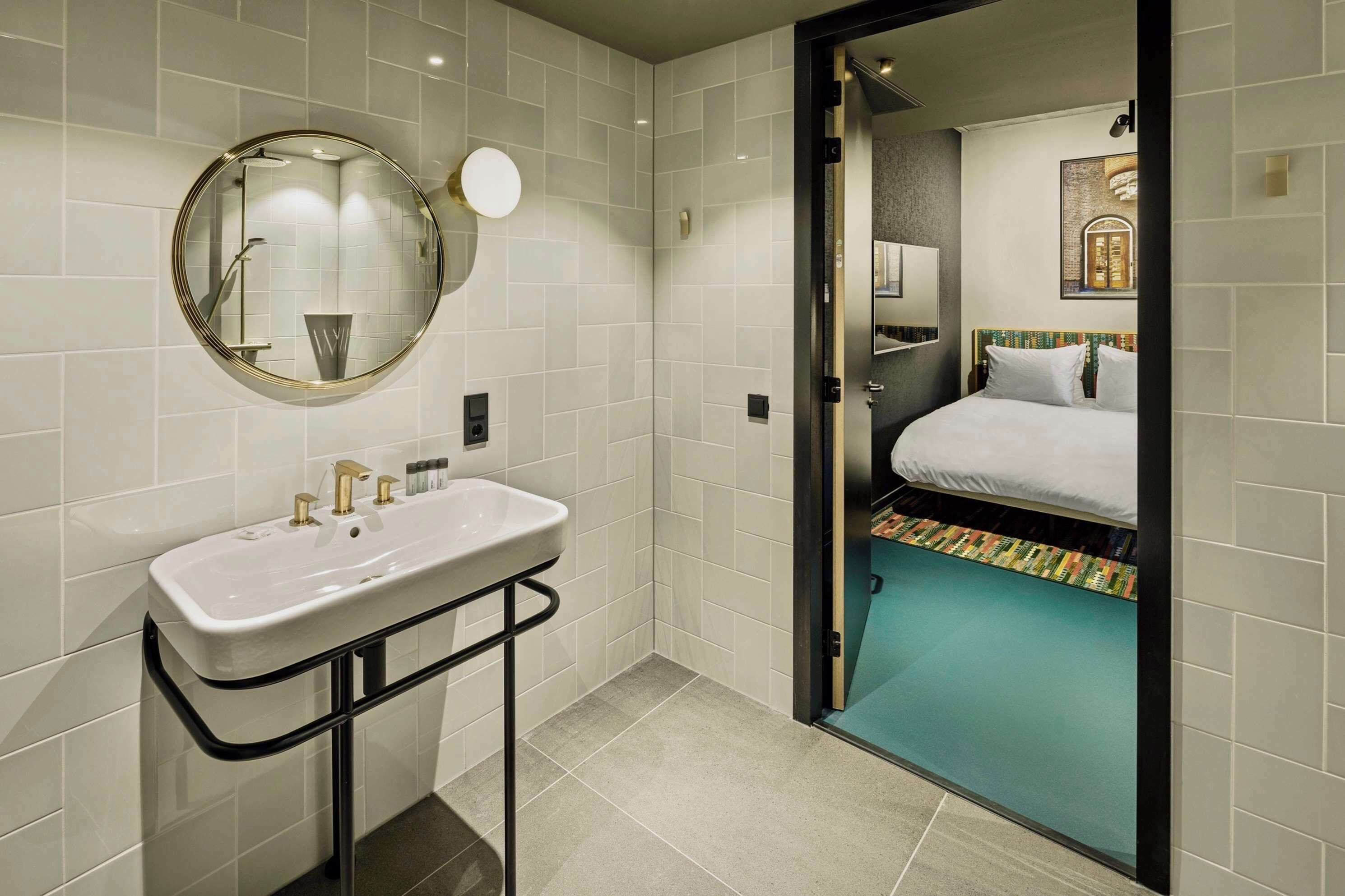Un baño moderno con lavamanos, espejo y ducha.