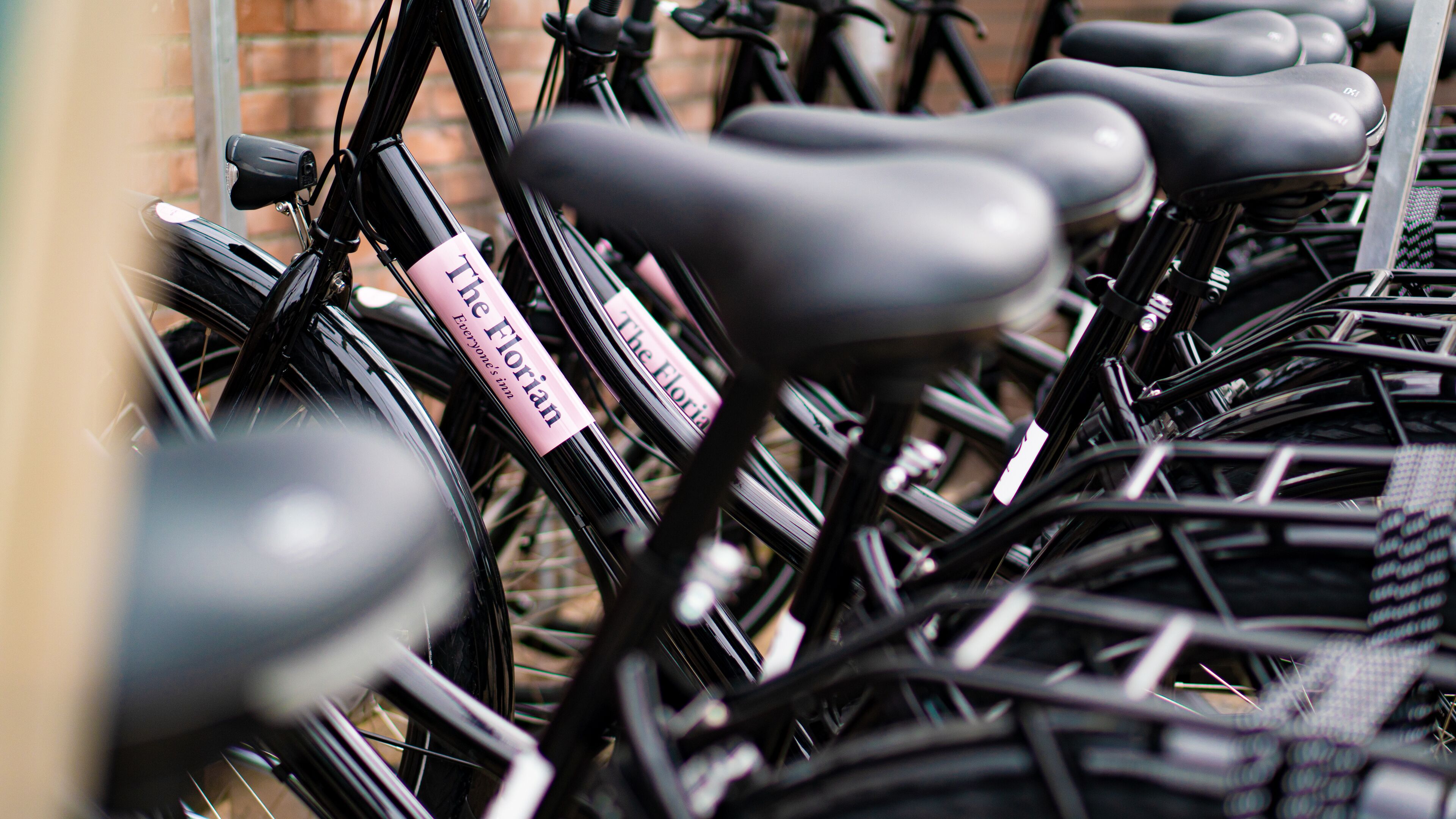 A row of bicycles with a pink sign attached to one of them.