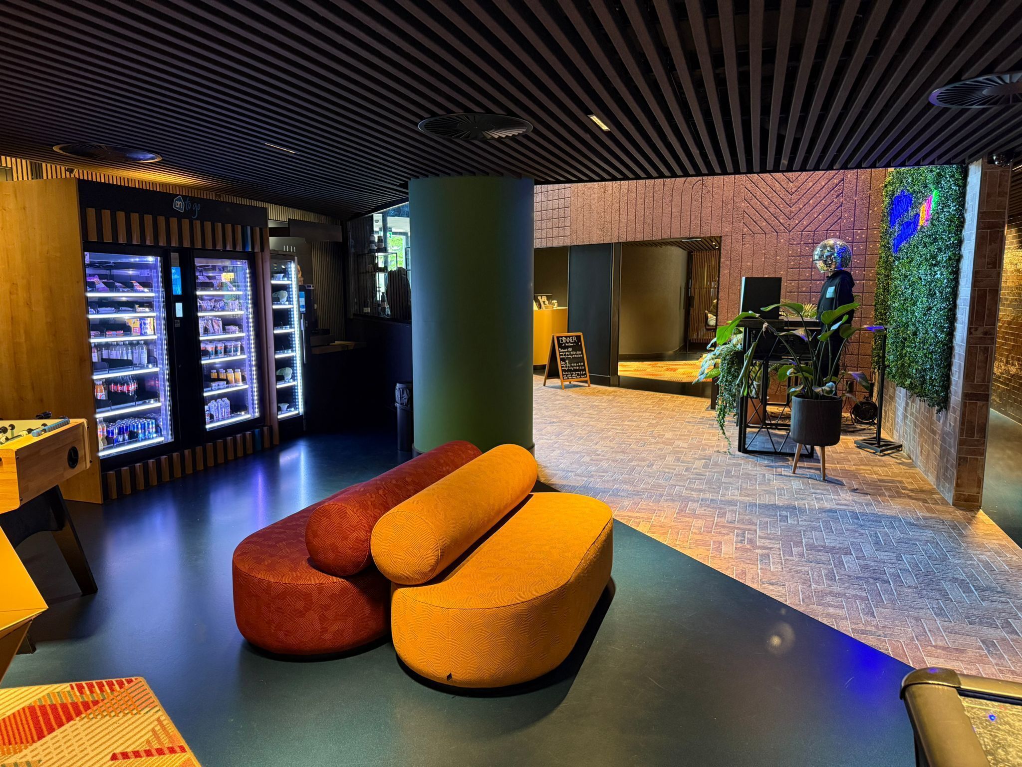 A modern lobby with seating areas, a vending machine, and a reception desk.