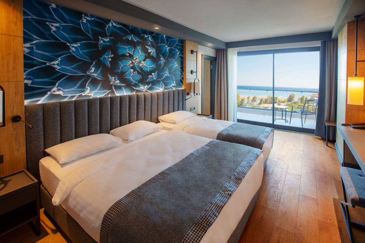 A hotel room with a large bed, a view of the sea, and a modern design.