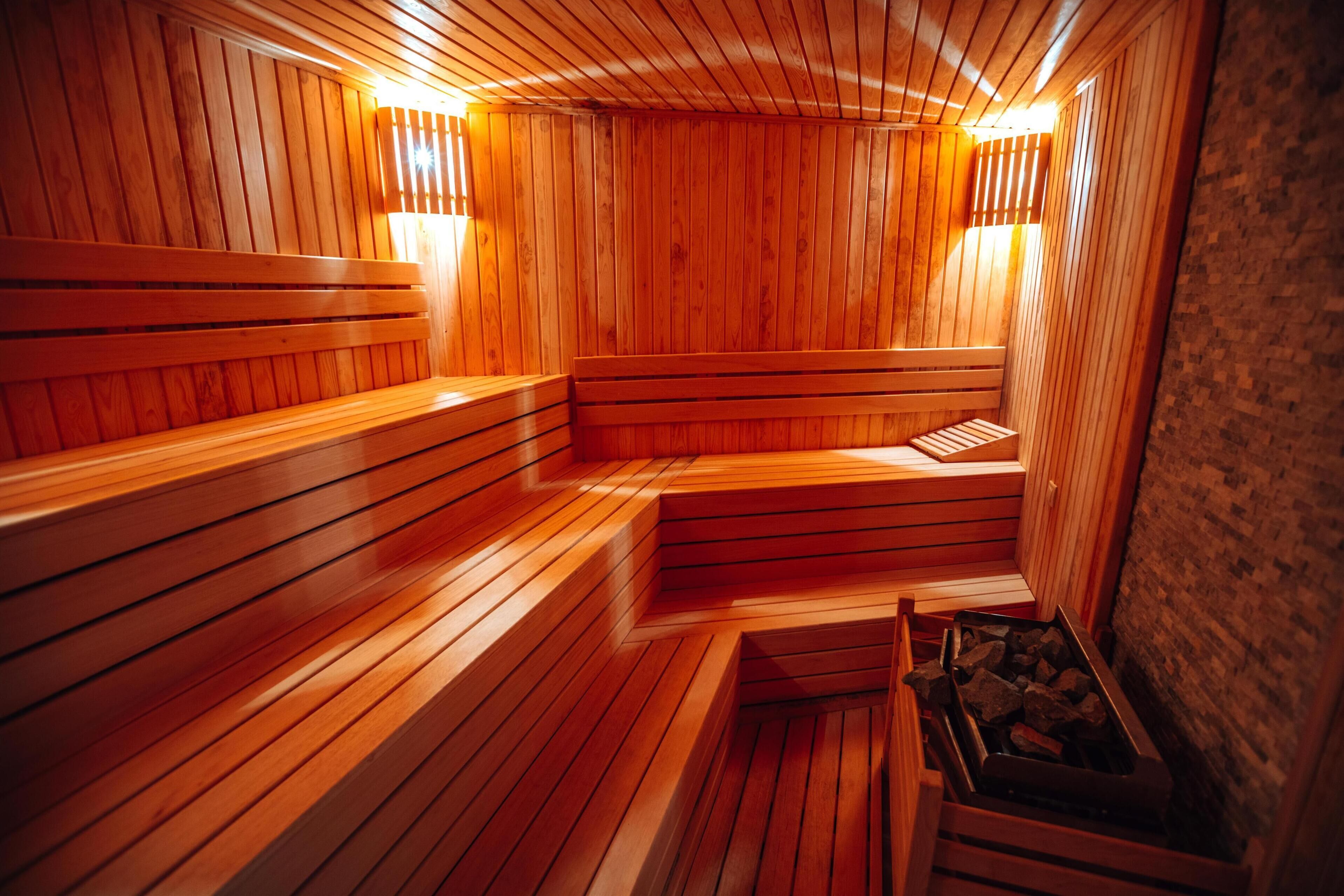 A sauna with wooden benches and benches, a brick wall, and a wooden floor.