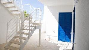 A white staircase leading to a balcony with a blue door. - Villa Sabbie D'oro (Cava D'aliga)