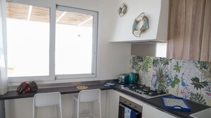A kitchen with a window, two white chairs, a stove, and a toaster. - Villa Sabbie D'oro (Cava D'aliga)