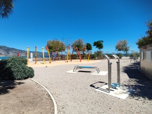 A playground with climbing structures and a wheelchair-accessible bench.