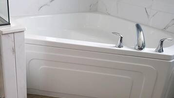 Een moderne badkamer met een vrijstaand bad, een witte wastafel en muren met een marmerlook.