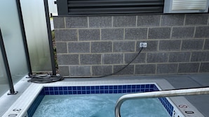 A hot tub with a metal safety rail, tiled edges, and a drain cover.