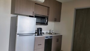 A compact kitchen with a refrigerator, microwave, coffee maker, and dishwasher.