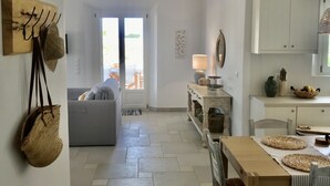 Un vaste espace de vie comprenant un canapé, une table à manger avec des sets de table en fibres naturelles, et un coin cuisine avec des placards et un plan de travail.