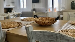 Un coin repas avec une table en bois, des sets de table en fibres tressées et un centre de table composé d’un panier tressé.