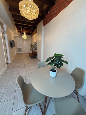 A dining area with a round table, four chairs, a potted plant, and a chandelier. - Penthouse Suite in Downtown New Orleans - 2 min FQ (New Orleans)
