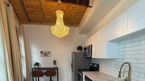 Una cocina moderna con armarios blancos, un lavamanos de acero inoxidable y un techo de madera.