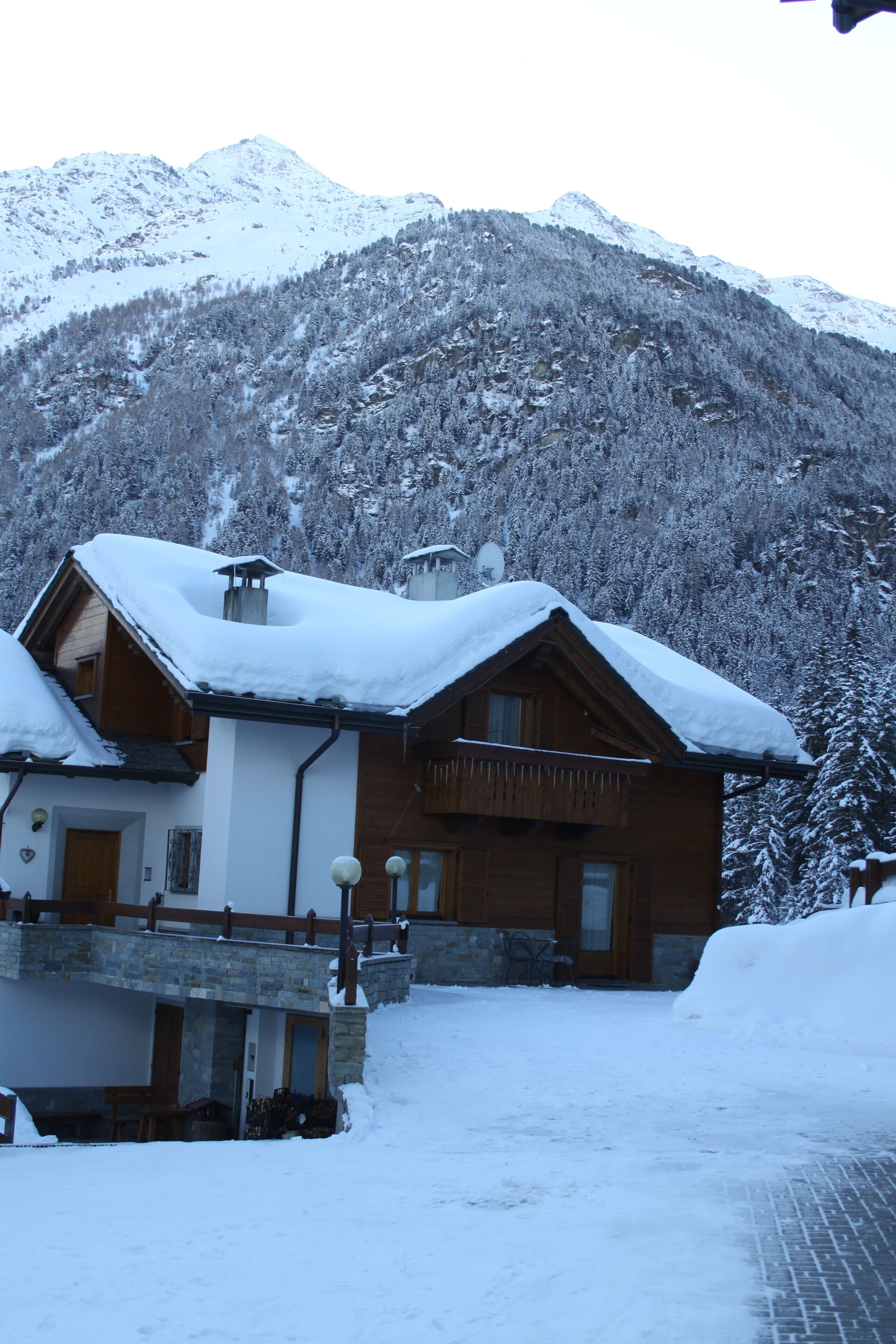 Eine Holzhütte mit schneebedecktem Dach in einer verschneiten Berglandschaft.