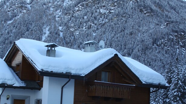 A wooden chalet with a snow-covered roof, situated in a snowy mountainous area. - THREE-ROOM APARTAMENT  2 BATHROOM
BIKE TREKKING  MOUNTAIN VALFURVA STELVIO GAVIA (Santa Caterina)