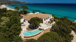 Una propiedad costera con piscina, un edificio blanco con arcos y vista al mar.
