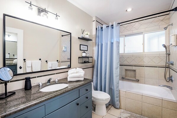 Un baño moderno con un espejo grande, un lavamanos, un inodoro y una bañera.