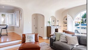 A spacious living room with a brown leather chair, a grey sofa, and a coffee table with a plant. - Spanish Home: Steps to Beach & 2nd St
-Quiet part of Belmont Shores (Long Beach)