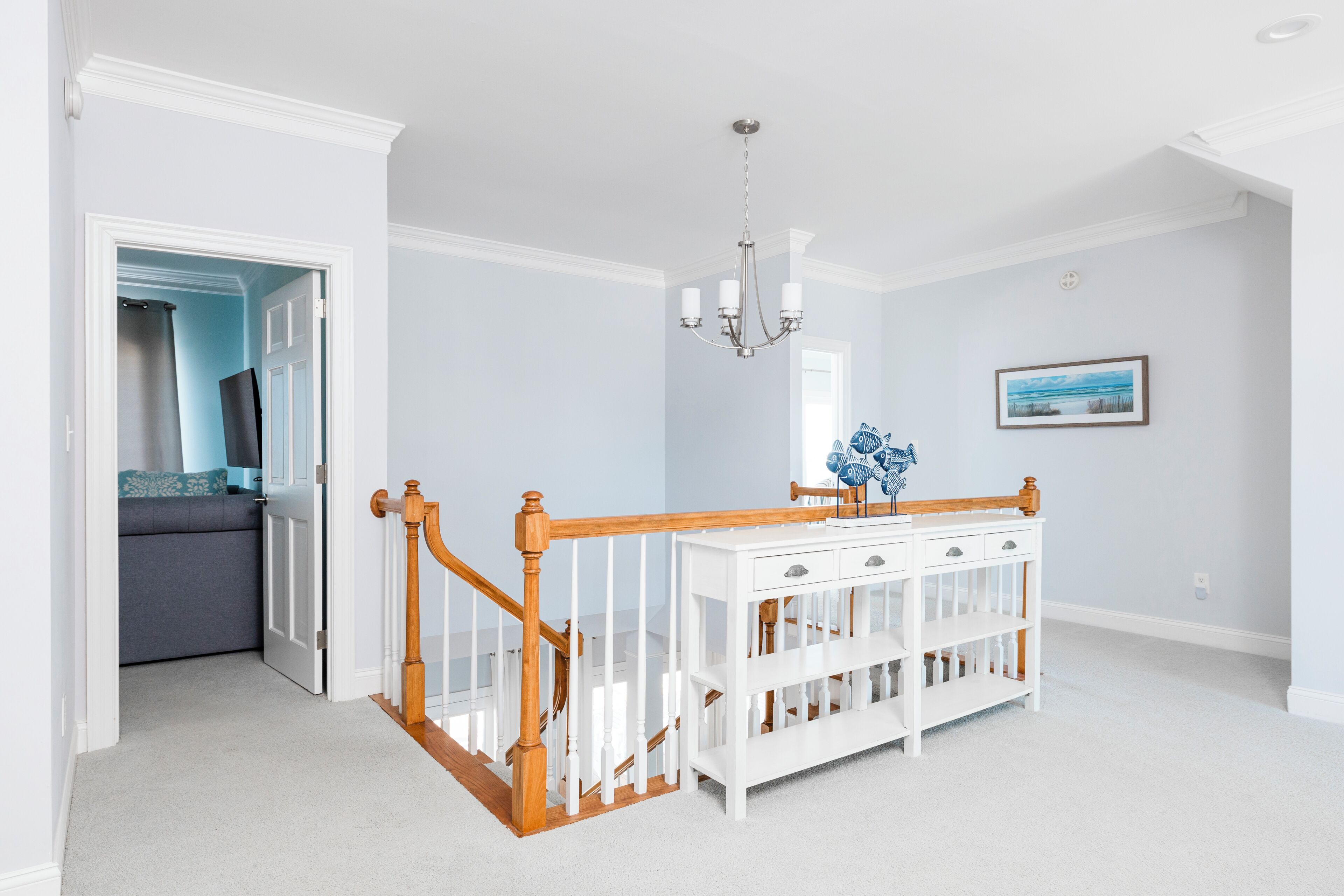 Une pièce avec un berceau blanc, un escalier en bois et un lustre.