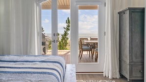 Une chambre à coucher comprenant un lit, une armoire et une porte donnant sur un patio extérieur avec une table et des chaises.